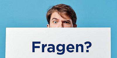 Kontakt GS1 Campus Ein junger Mann schaut über den Rand eines weißen Kartons