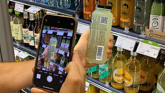 Scan eines 2D-Codes auf einer Jake's Lemonade Flasche am Kühlregal mit einem Smartphone