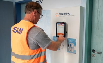 LKW-Fahrer checkt an Bildschirm der Self-Service-Lösung von Cloud4Log ein