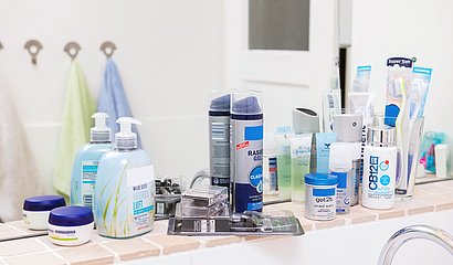 Kostmetikprodukte auf Ablage vor Badezimmerspiegel