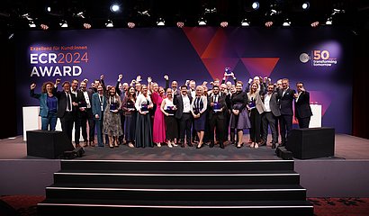 Gruppenbild der jubelnden Gewinnerteams vom ECR Award 2024 auf großer Bühne mit Trophäen