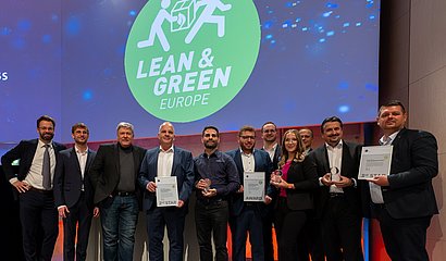 Preisträger:innen der Lean and Green Auszeichnungen zusammen mit GS1 Germany auf dem DLK 2023 auf der Bühne vor Lean and Green Logo